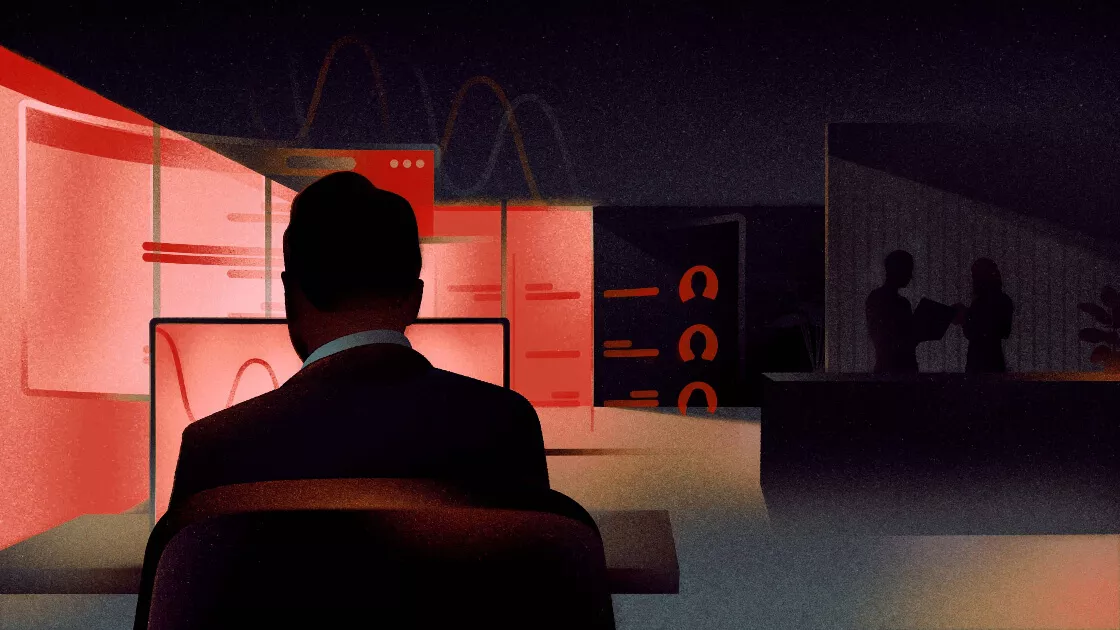 Cybersecurity trends 2024: a male figure looking at a computer screen in office surroundings, pictured from behind.