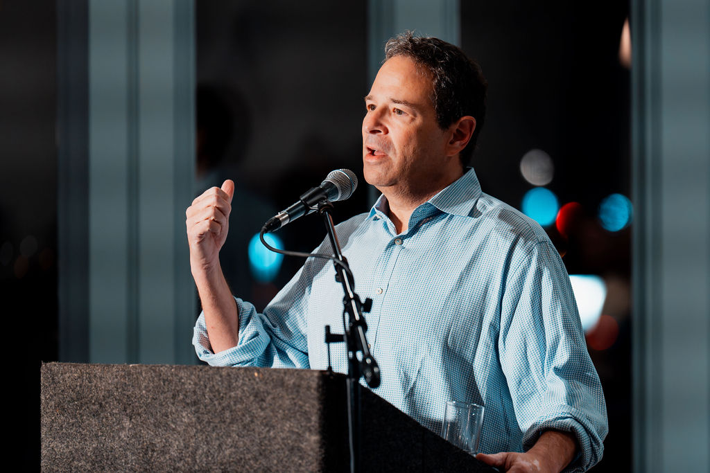 Rich Cohen speaking at a stand with a microphone