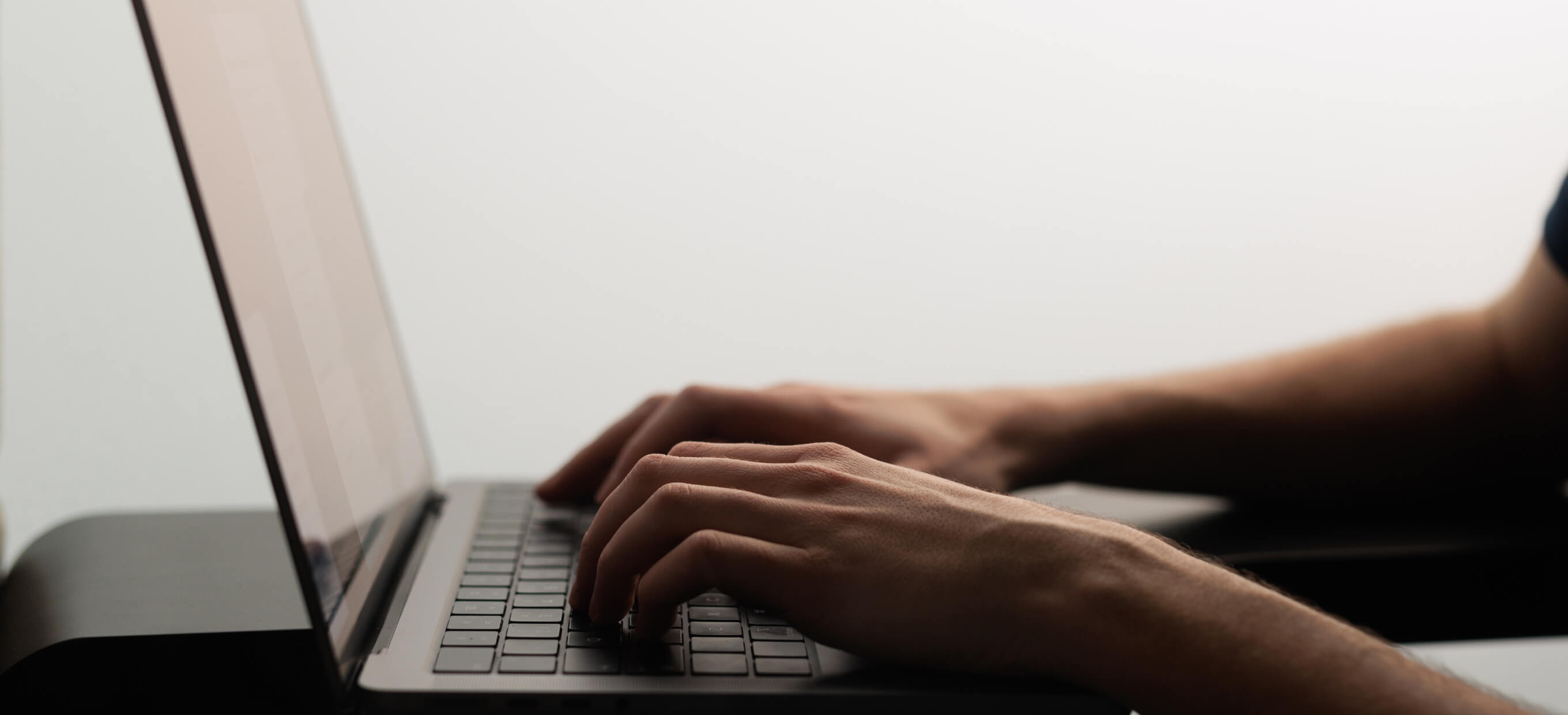 Person using a smartphone and laptop simultaneously, representing mobile and web app development solutions for seamless digital experiences.